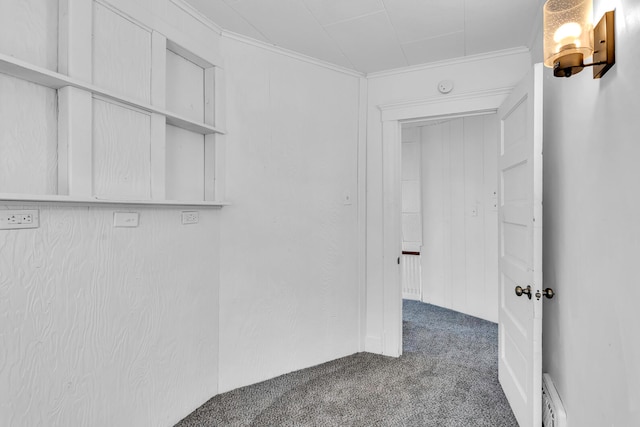 hallway with ornamental molding and dark colored carpet