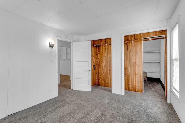 unfurnished bedroom with carpet flooring and wood walls