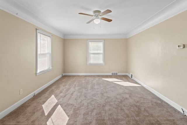 empty room featuring ceiling fan, light colored carpet, and crown molding