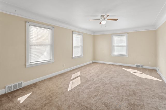 carpeted spare room featuring ceiling fan and crown molding