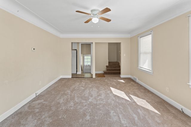 carpeted empty room with ceiling fan and crown molding