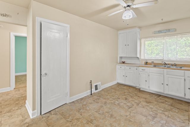 kitchen with ceiling fan, sink, and white cabinets