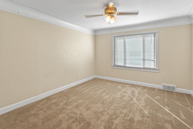 empty room featuring ceiling fan, carpet floors, and crown molding