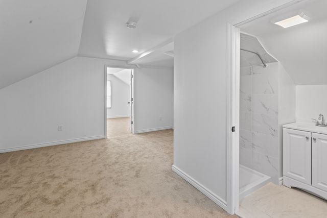 bonus room with light carpet, sink, and lofted ceiling