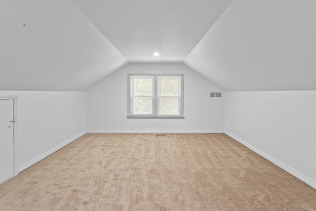 bonus room with light colored carpet and vaulted ceiling