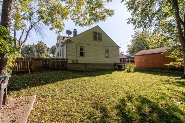 back of house featuring central AC unit and a yard