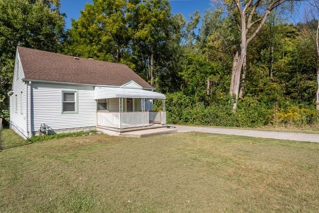 rear view of house featuring a porch and a lawn