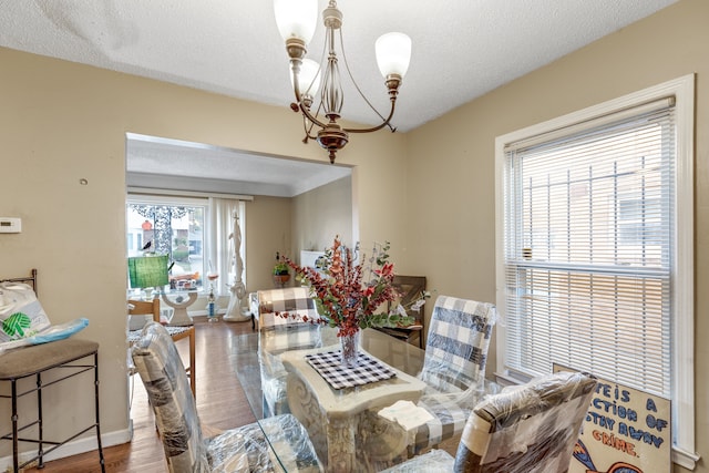 dining space with hardwood / wood-style floors, a textured ceiling, and an inviting chandelier