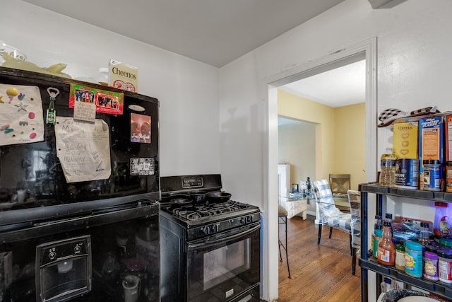 kitchen with hardwood / wood-style flooring and black appliances