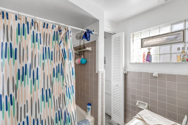 bathroom featuring shower / bathtub combination with curtain and tile walls