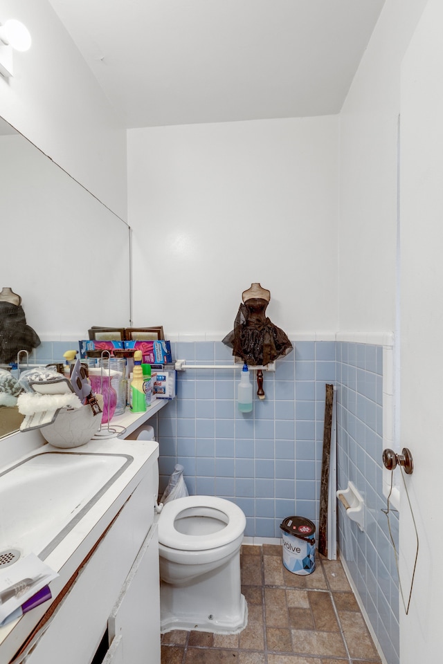 bathroom featuring vanity, tile walls, and toilet