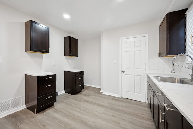 kitchen with decorative backsplash, dark brown cabinetry, light hardwood / wood-style flooring, and sink