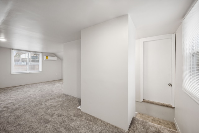 interior space with a wall mounted air conditioner, lofted ceiling, and carpet floors