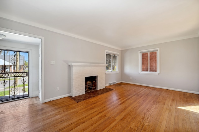 unfurnished living room featuring crown molding, light hardwood / wood-style floors, and a brick fireplace