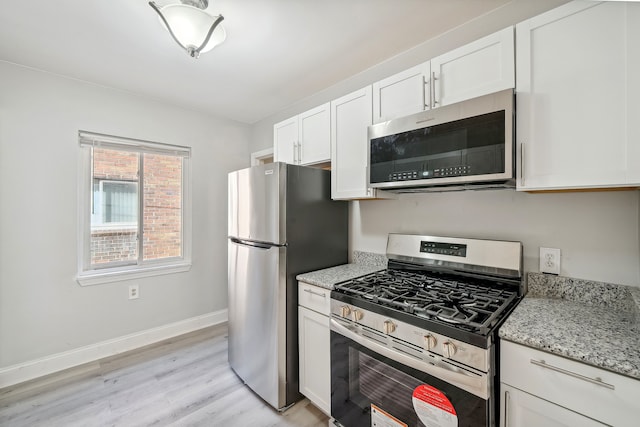 kitchen featuring white cabinets, light hardwood / wood-style floors, light stone countertops, and appliances with stainless steel finishes