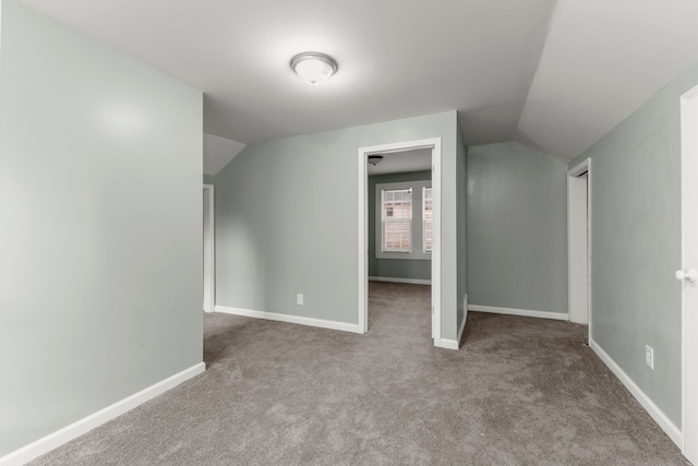 bonus room with light colored carpet and vaulted ceiling