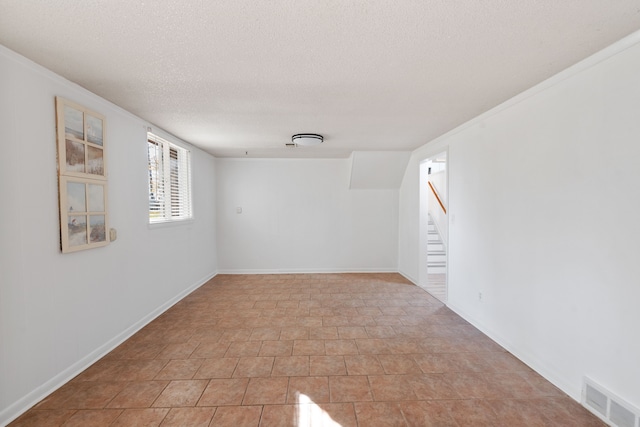 tiled spare room featuring a textured ceiling