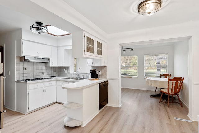 kitchen featuring stainless steel gas stovetop, light hardwood / wood-style flooring, black dishwasher, tasteful backsplash, and white cabinetry