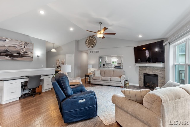 living room featuring vaulted ceiling, ceiling fan, built in desk, hardwood / wood-style flooring, and a fireplace