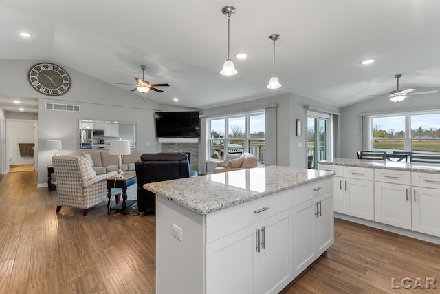 kitchen featuring a center island, pendant lighting, vaulted ceiling, white cabinets, and hardwood / wood-style flooring