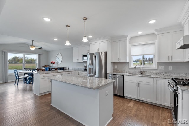 kitchen with white cabinetry, a kitchen island, stainless steel appliances, and vaulted ceiling