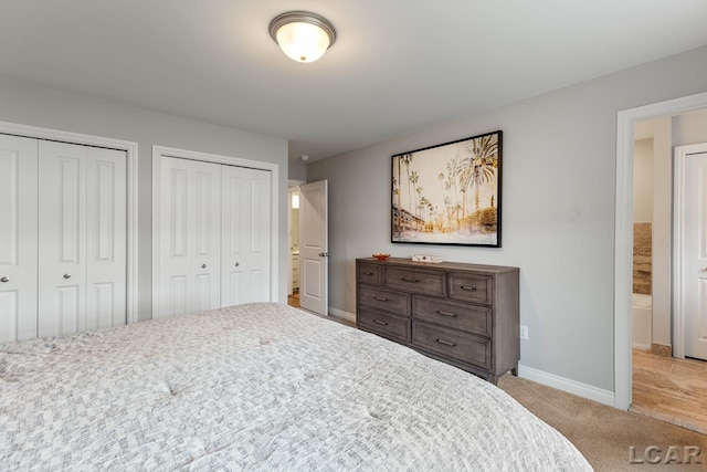 bedroom featuring light colored carpet and two closets