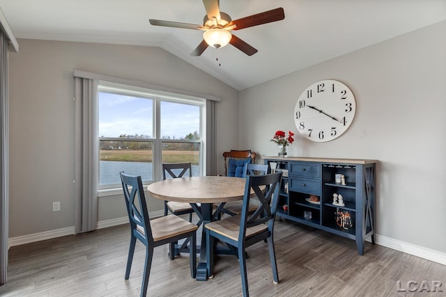 dining room with a water view, hardwood / wood-style flooring, lofted ceiling, and ceiling fan