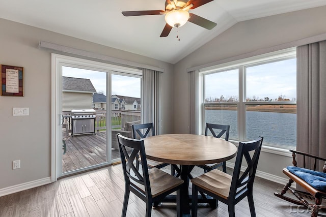 dining area with plenty of natural light, a water view, wood-type flooring, and vaulted ceiling