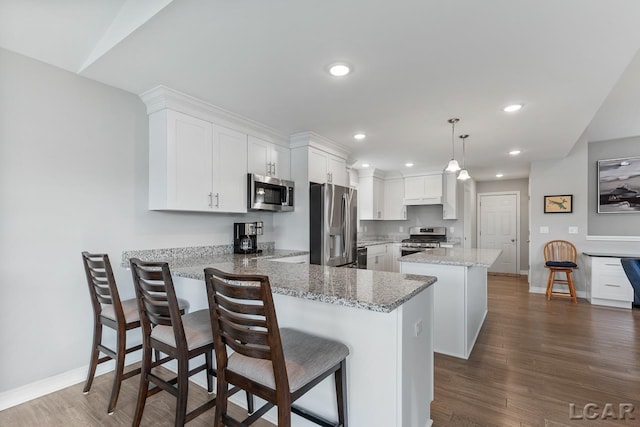 kitchen featuring white cabinetry, dark wood-type flooring, stainless steel appliances, kitchen peninsula, and decorative light fixtures