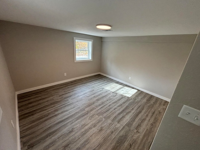 empty room with dark hardwood / wood-style floors and lofted ceiling