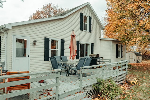 rear view of house featuring a wooden deck and a storage shed