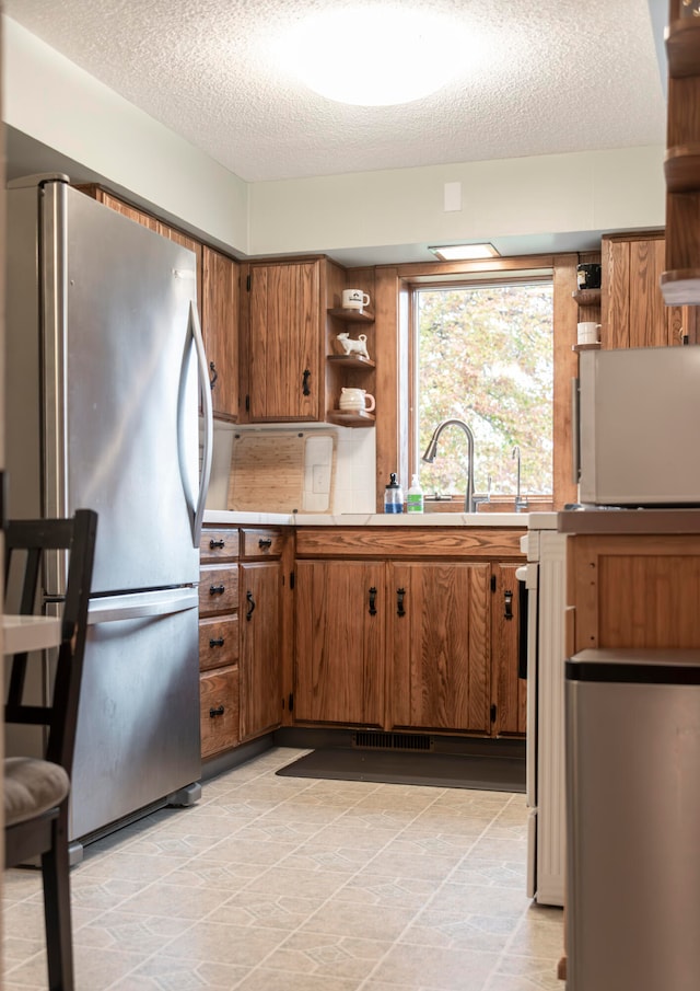 kitchen featuring stainless steel fridge and a textured ceiling