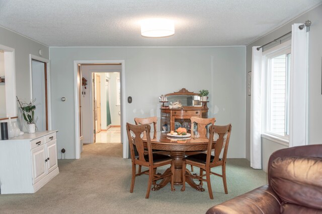 dining space featuring light colored carpet and a textured ceiling