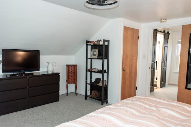 carpeted bedroom with a barn door and lofted ceiling