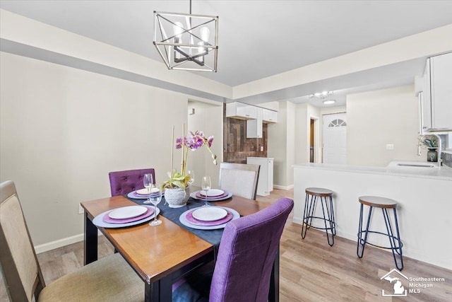 dining room with light hardwood / wood-style floors, sink, and an inviting chandelier