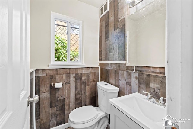 bathroom featuring vanity, toilet, and tile walls