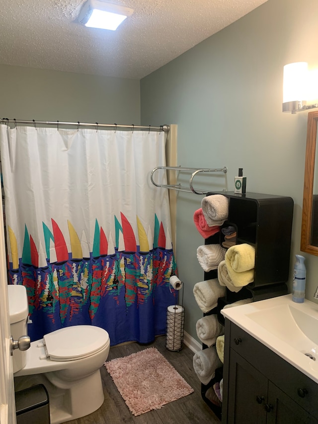 bathroom featuring curtained shower, hardwood / wood-style floors, a textured ceiling, toilet, and vanity