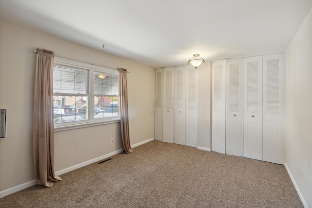 unfurnished bedroom featuring carpet floors and two closets