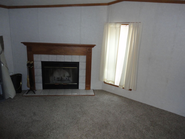 unfurnished living room with a tiled fireplace, crown molding, and light colored carpet