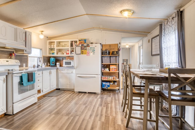 kitchen featuring lofted ceiling, white appliances, white cabinets, light wood-type flooring, and a textured ceiling