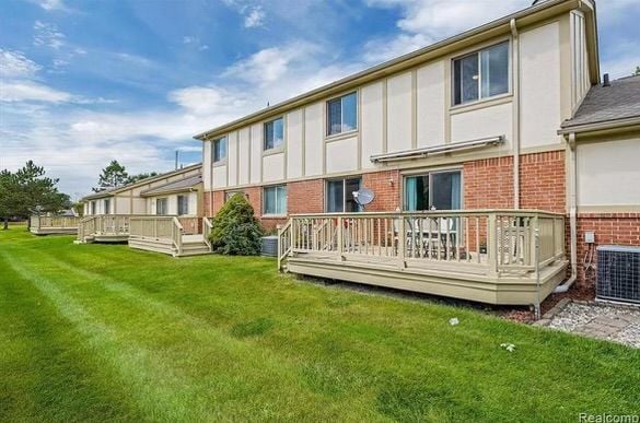 back of property featuring a lawn, central AC unit, and a wooden deck