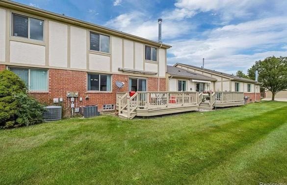 back of property with central AC unit, a deck, and a yard