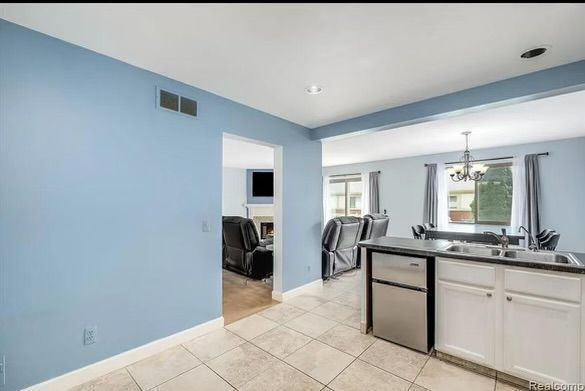 kitchen with white cabinetry, sink, hanging light fixtures, a notable chandelier, and light tile patterned floors