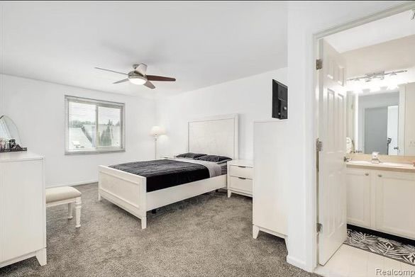 bedroom featuring ceiling fan, light carpet, and connected bathroom