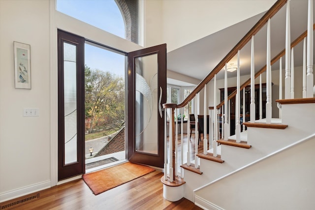 entryway with plenty of natural light, hardwood / wood-style floors, and a high ceiling