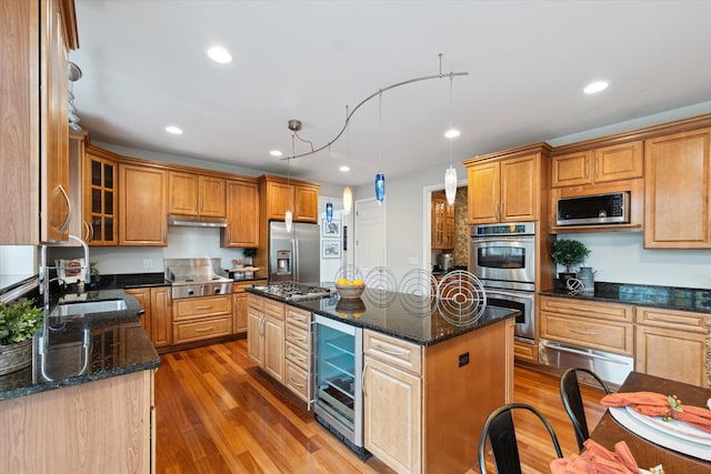 kitchen featuring hardwood / wood-style floors, pendant lighting, wine cooler, appliances with stainless steel finishes, and a kitchen island