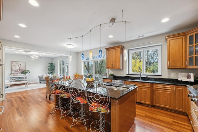 kitchen featuring sink, a center island, light hardwood / wood-style flooring, decorative light fixtures, and a breakfast bar