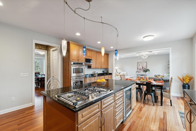 kitchen with beverage cooler, a kitchen island, stainless steel appliances, and light wood-type flooring