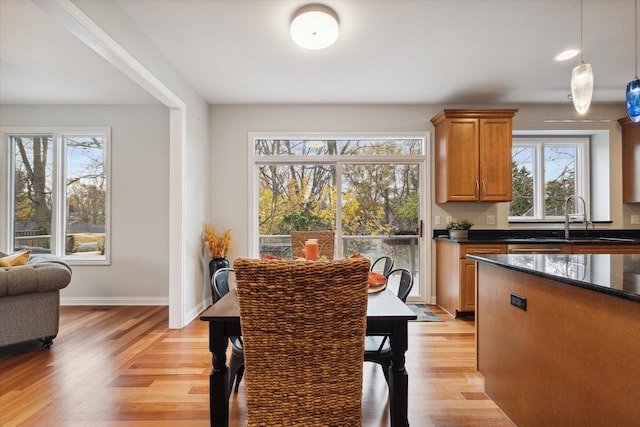 dining space with plenty of natural light, sink, and light hardwood / wood-style flooring