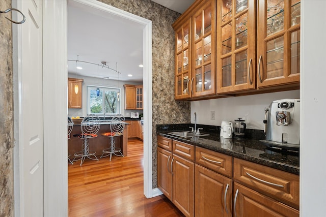 interior space featuring hardwood / wood-style flooring, dark stone countertops, and sink